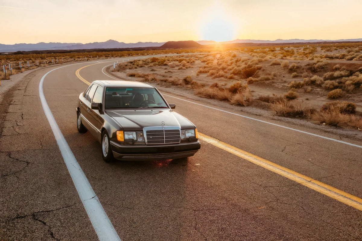 Mercedes-Benz W124 E-Class saloon on a desert road at sunset
