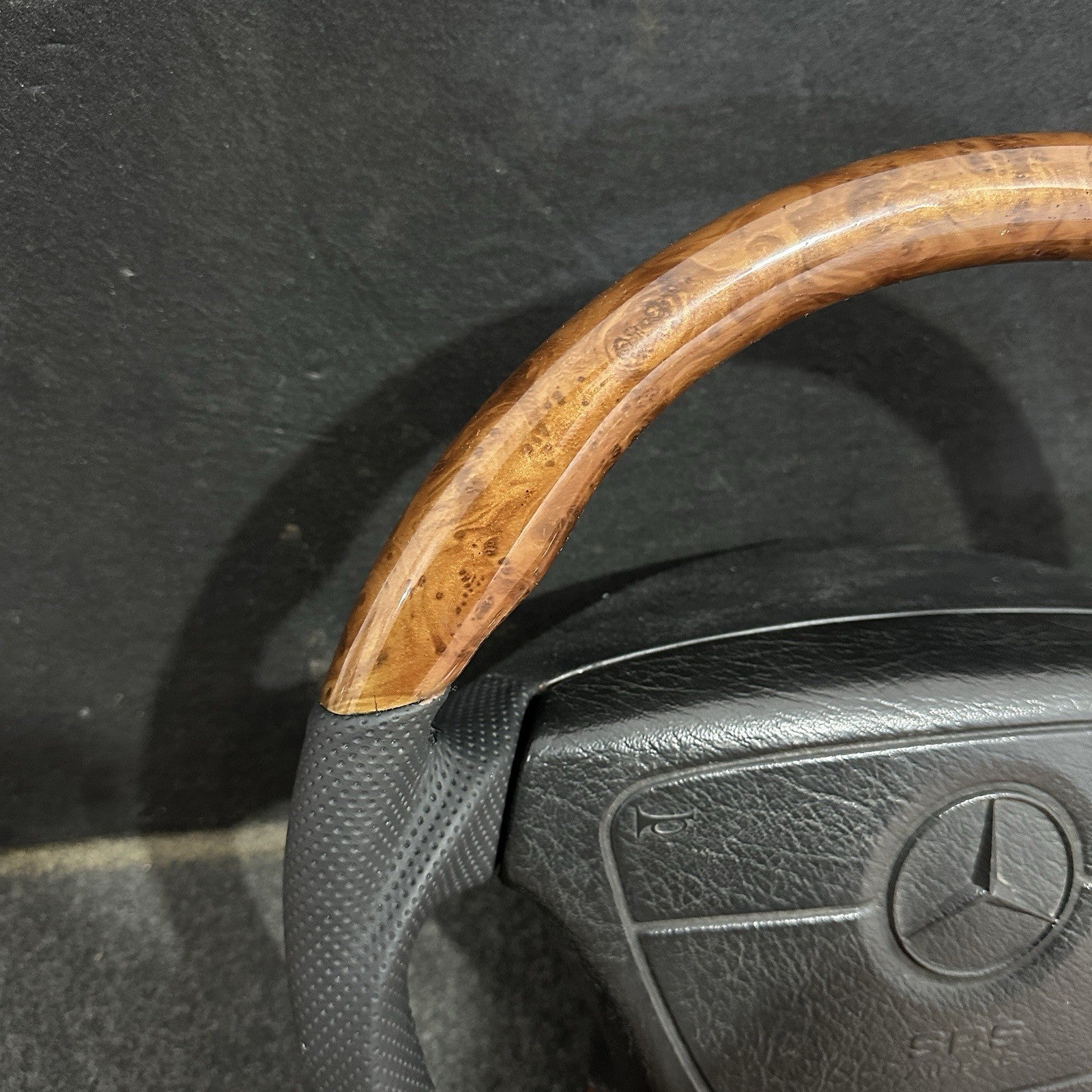 Close-up of premium black perforated leather stitching on a refurbished Mercedes-Benz steering wheel.