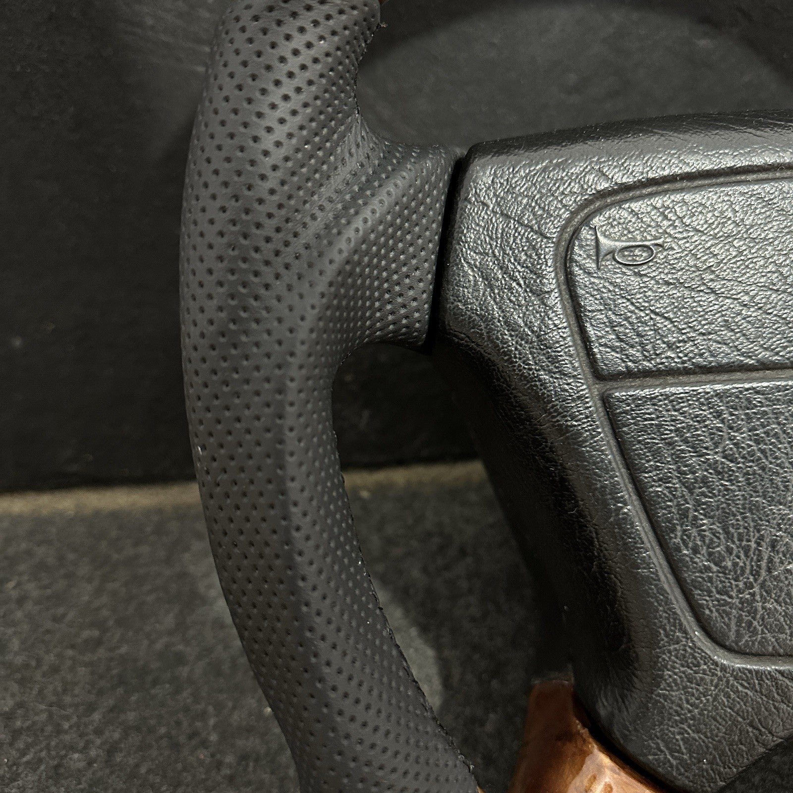 Close-up of premium black perforated leather stitching on a refurbished Mercedes-Benz steering wheel.
